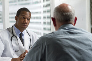 A doctor talking to another man in front of him.